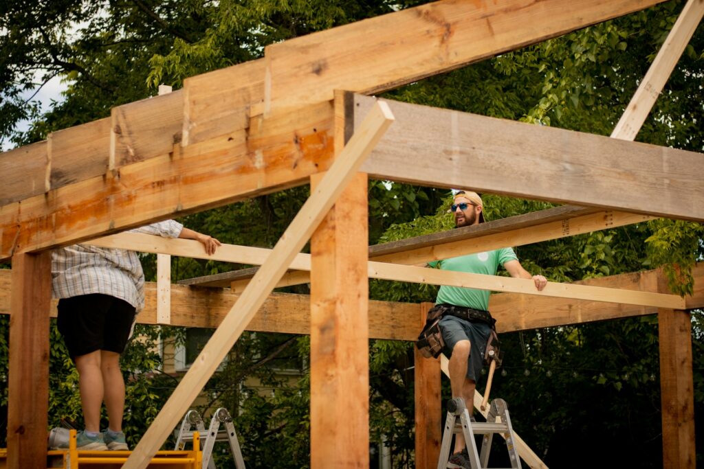 Photo by Conor Brown woman in blue jacket and blue denim jeans standing on brown wooden bridge