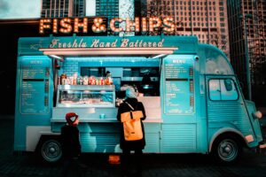 woman in brown coat standing in front of food stall