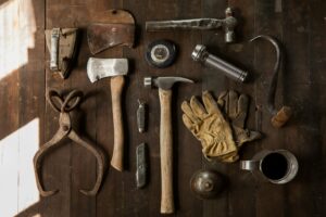 clothes iron, hammer, axe, flashlight and pitcher on brown wooden table